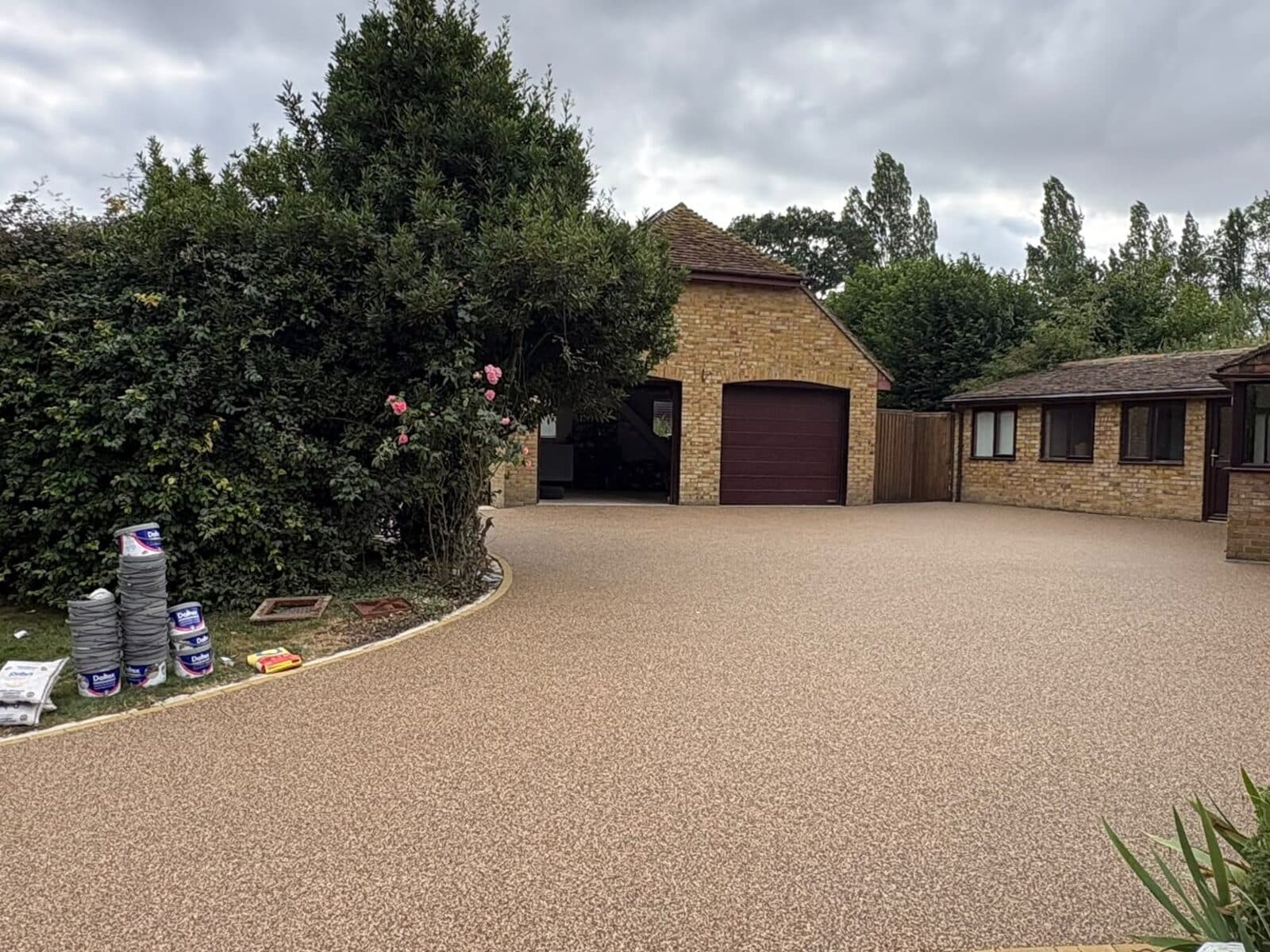 Golden resin-bound driveway sweeping up to a brick house and garage