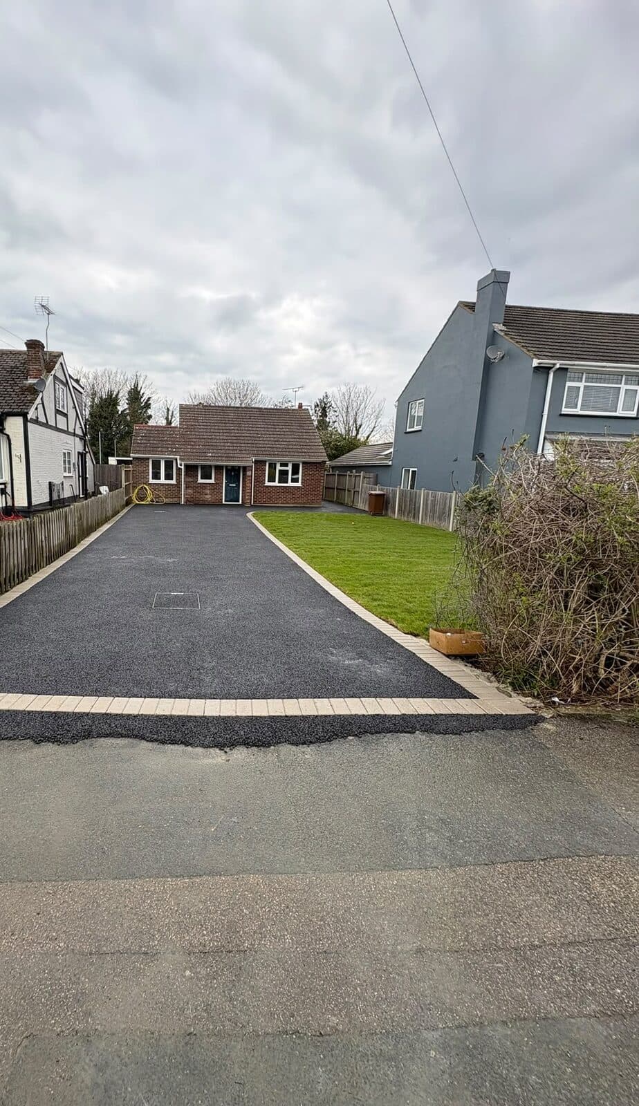 Tarmac driveway with a block paved border tying into a newly laid lawn in front of a house